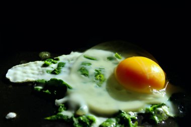 Ispanak yakın çekim ile bir tavada kızarmış yumurta üst görünüm. Kahvaltı yüksek açı çekim. Diyet ve beslenme kavramı - düz yumurtalı omlet ve ıspanak.