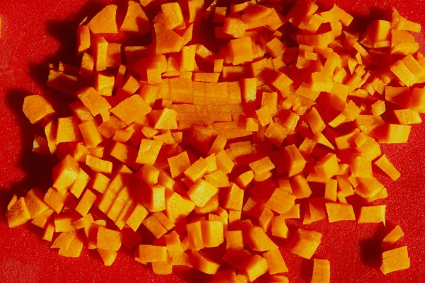 食品の背景 赤い背景にニンジンを細かくみじん切り 新鮮なニンジン — ストック写真