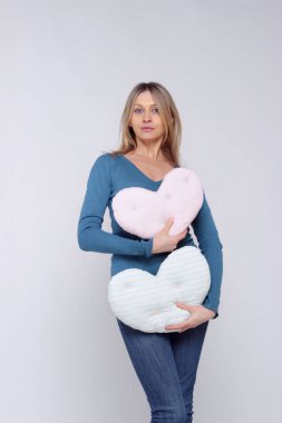 Bir kalp şekilli yastıklar tutan genç bir kadın portresi. Genç kız eğlenin. İnsanlar, sağlık, eğlence konsepti. 