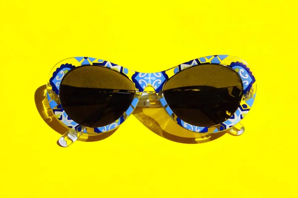 夏季概念 黄色背景的蓝色太阳镜 彩色相框中太阳镜的顶视图 — 图库照片