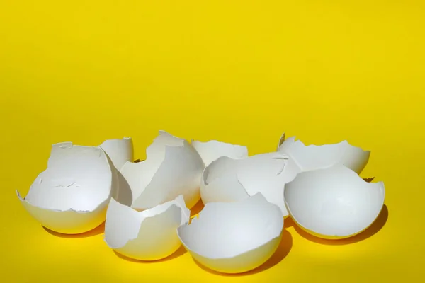 抽象的な食品成分 ひび割れた卵がクローズアップ 壊れた白鶏の卵殻 黄色の背景の上に白い卵殻 カラフルな背景 — ストック写真