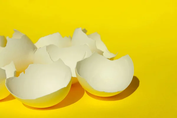 抽象的な食品成分 ひび割れた卵がクローズアップ 壊れた白鶏の卵殻 黄色の背景の上に白い卵殻 カラフルな背景 — ストック写真