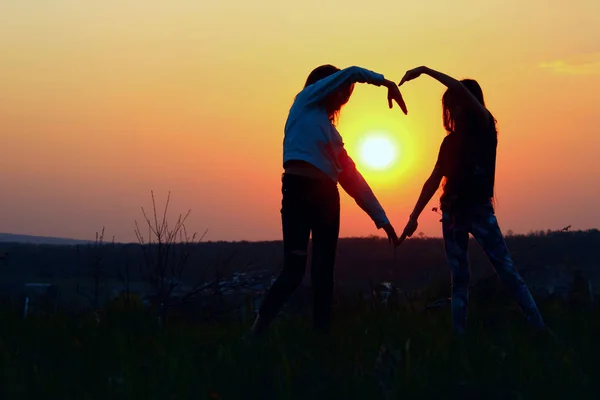 Young Female Couple Making Heart Shape With Hands At Sunset. Abstract Love Background. People, Love, Friendship Background. Female Best Friends Making A Heart.