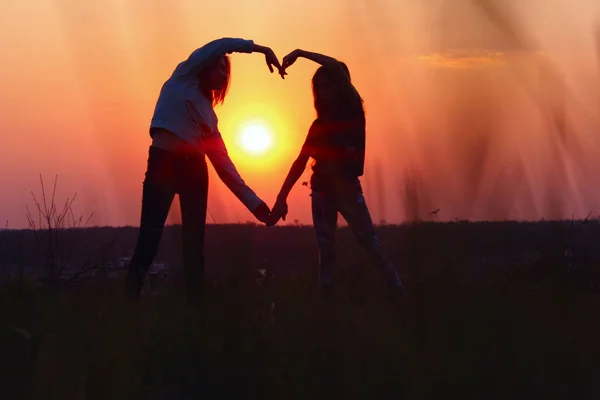 Young Female Couple Making Heart Shape With Hands At Sunset. Abstract Love Background. People, Love, Friendship Background. Female Best Friends Making A Heart.