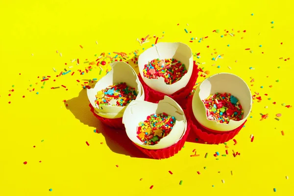 黄色の背景に多色キャンディスイーツ 卵殻の中の多色の小さなキャンディーのクローズアップ ミニマルなアートデザイン デザート 誕生日のコンセプト 壊れた卵とカラフルなキャンディー — ストック写真