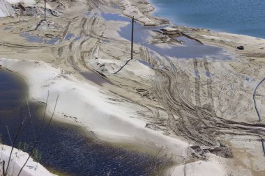 Gölden çok uzak olmayan ıslak kumda lastik izleri. Soyut doğa arka planı. Yol.