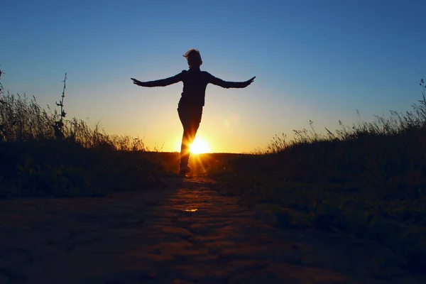 Young Girl Jumping Over Sunset Background. Full Length Silhouette Of A Happy Girl  Running Outdoors. People, Travel Concept.