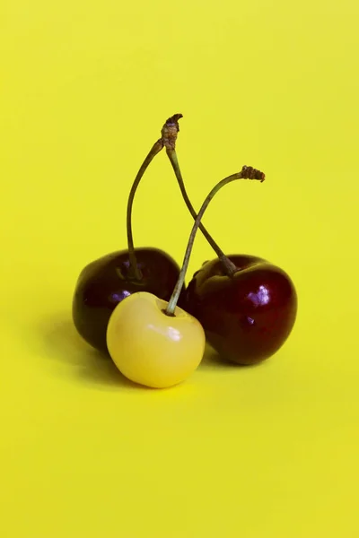 Yellow and red cherry on yellow background. Abstract food background.