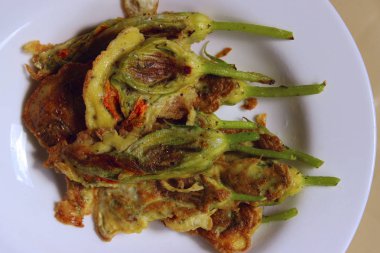 Tabakta kızarmış kabak çiçekleri. Sıradışı yemek konsepti. Meyilli kabak çiçekleri.