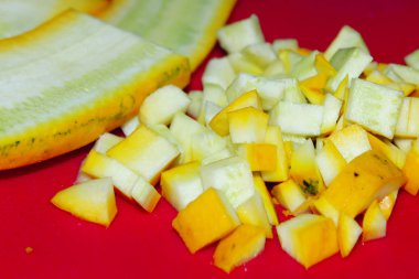 Kırmızı arka planda sarı kabak kırpılmış vurdu. Yemek, pişirme konsepti. Kabak, pişirme süreci.