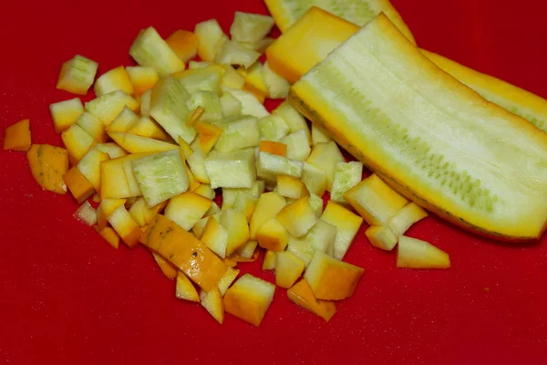 Cropped shot of yellow zucchini over red  background. Food, cooking  concept. Zucchini, cooking process.