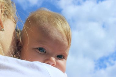İnsanlar, çocukluk, aile kavramı. Mavi gökyüzü arka plan üzerinde sevimli bir kız bebek kırpılmış çekim. Kız kardeşler kucaklaşır, yakınlaşır. 