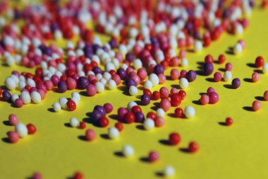 Sarı arkaplanda renkli şekerlerin bulanık görüntüsü. Tatlı malzemesi. Soyut renkli arkaplan.