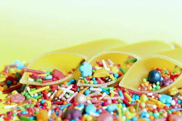 概要食品の背景 黄色の背景にデュラム小麦パスタとカラフルなキャンディー 互換性のない製品コンセプト — ストック写真