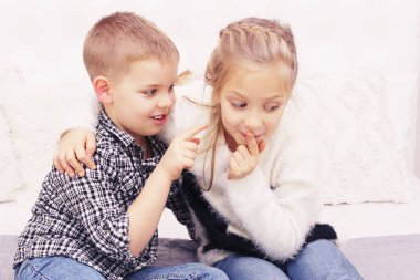 İnsanlar, mutluluk, arkadaş canlısı aile, çocuklar, aile değeri kavramı. Erkek ve kız kardeş oynuyor. Kız ve erkek konuşuyor. Ablam ve küçük erkek kardeşi oturuyor.. 