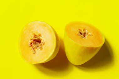 Sarı karpuz sarı arkaplanda ikiye bölünmüş, yakın görüş. Soyut gıda arka planı, sarı renkler.