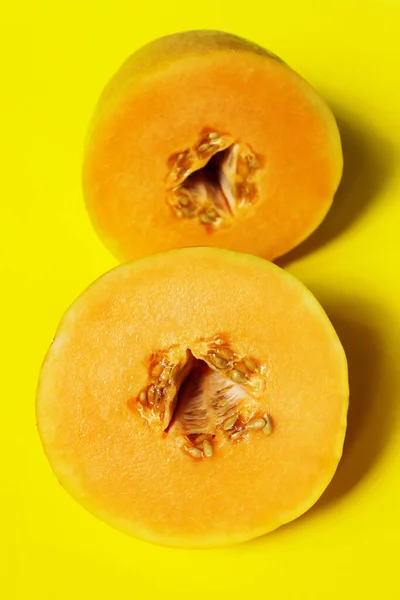 Yellow melon cut in two on yellow background, close up view. Abstract food background, yellow colors.