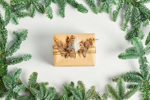 holiday concept. frame of green spruce branches. beautiful hand made gift wrapping. natural jewelry made of feathers, twine and craft paper. top view, flat lay.