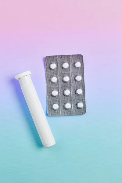 creative medicine compositions. white pill pack and silver blister pack on gradient background. vitamins for skin, hair, and nails. flat lay, vertical frame.