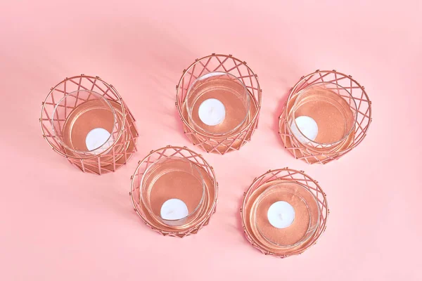 composition of candlesticks in rose gold and white candles on a pink background. top view, flat lay.