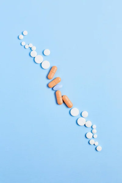 composition of pills on a blue background. vitamins for skin, hair, and nails. wellness concept. creative layout, top view.