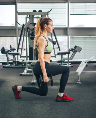 Genç kız spor salonunda egzersiz yapıyor.