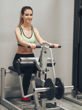Genç kız spor salonunda egzersiz yapıyor.