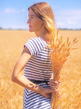 Genç bir kadın, güneşli gökyüzünün altındaki buğday tarlasında