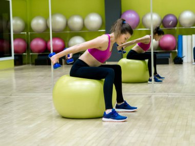 Genç model kız spor salonunda aynanın önünde egzersiz yapıyor. 