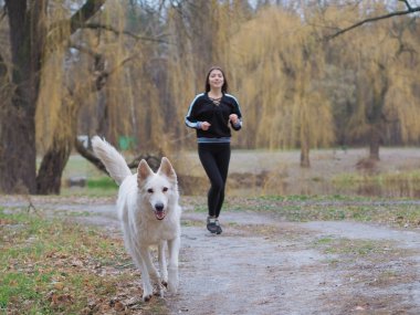 Ormanda koşan köpeği olan genç bir kız.