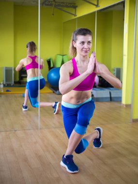 Genç model kız spor salonunda aynanın önünde egzersiz yapıyor. 