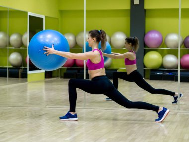 Genç model kız spor salonunda aynanın önünde egzersiz yapıyor. 