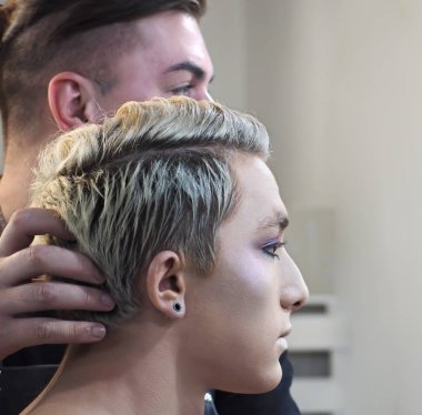 Makyaj sanatçı ve genç erkek model aynaya bakarak