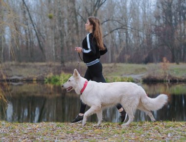 Ormanda koşan köpeği olan genç bir kız.