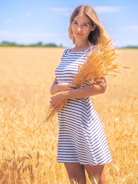 Mladá žena na pšeničném poli pod modrou oblohou za slunečného dne — Stock fotografie