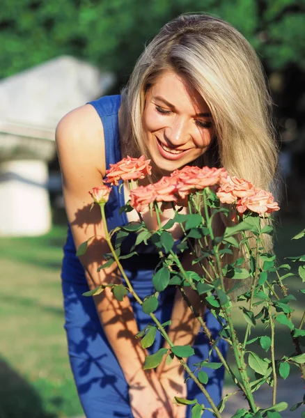 Blonde model op de heldere zon poseren in de buurt van roze rozen — Stockfoto