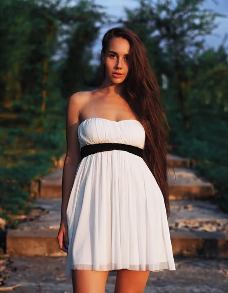 Jong brunette model op de witte jurk verblijf op de trap wi — Stockfoto