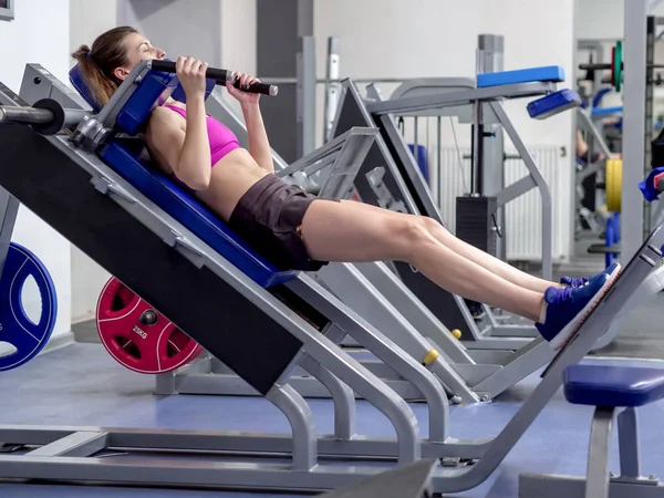 Chica modelo joven hace ejercicios en el gimnasio frente al espejo — Foto de Stock