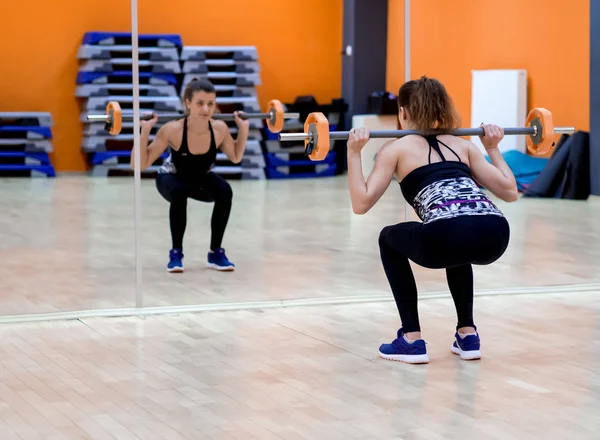 Jong model meisje maakt oefeningen in de sportschool in de voorkant van spiegel — Stockfoto