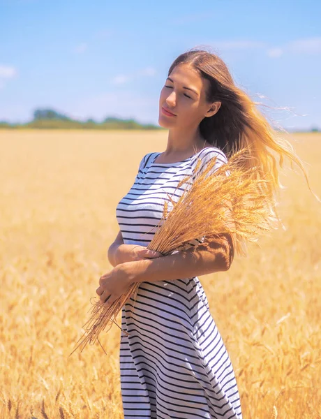 Mladá žena na pšeničném poli pod modrou oblohou za slunečného dne — Stock fotografie