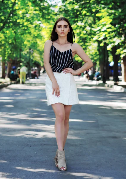 Chica joven modelo posando en el parque con árboles verdes —  Fotos de Stock