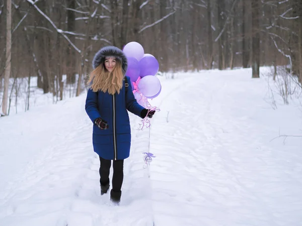 Młoda dziewczyna w niebieskim płaszczu z balonami w lesie — Zdjęcie stockowe