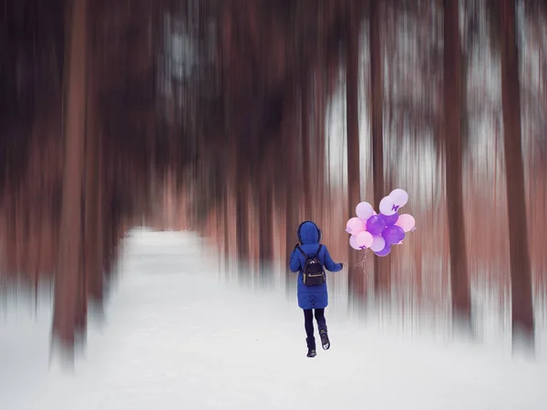 Mladá dívka v modrém kabátě s balónky v lese — Stock fotografie