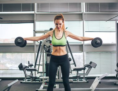 Genç kız spor salonunda egzersiz yapıyor.
