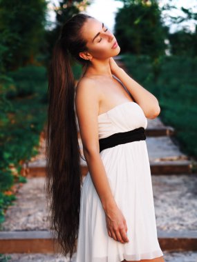 Beyaz elbiseli genç esmer manken merdivenlerde kalıyor.