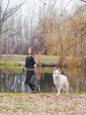 Ormanda koşan köpeği olan genç bir kız.