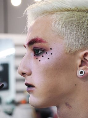 Makyaj sanatçı makyaj sarışın erkek modeli yakın çekim yapar