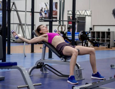 Genç model kız spor salonunda aynanın önünde egzersiz yapıyor. 