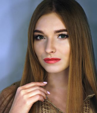 Kırmızı dudaklı ve yeşil gözlü genç kız kameraya bakıyor.