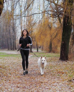 Ormanda koşan köpeği olan genç bir kız.